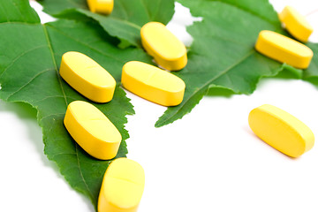 Image showing yellow vitamin pills over green leaves