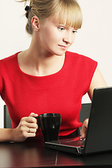 Image showing Blonde businesswoman in red working on laptop