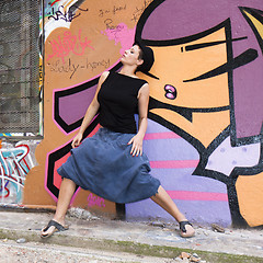 Image showing A young woman dancing in front of a wall