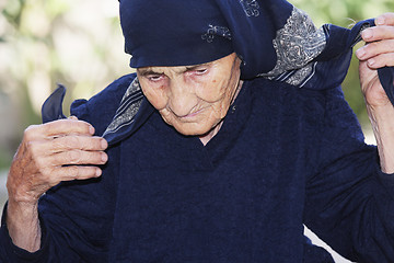 Image showing Senior woman ties up head with scarf