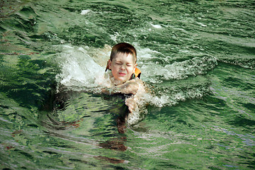 Image showing Boy eyes closed swimming with dolphin