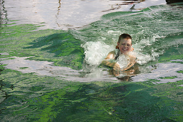 Image showing Smiling boy swimming with dolphin