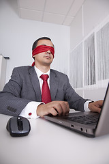 Image showing Blindfold businessman working with his laptop