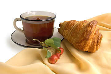 Image showing Brown glass cup with tea and croissants