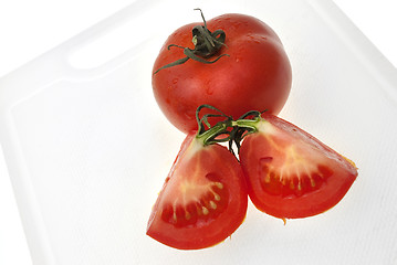 Image showing Cutting white plastic board with red tomato