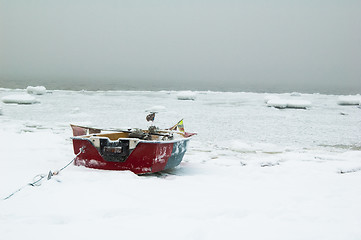 Image showing Fishing boat on the bank of the frozen sea