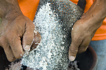 Image showing native man grating coconut