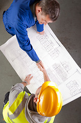 Image showing Builders shake hands over blueprint