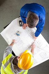 Image showing Builders talk about blueprint on bench