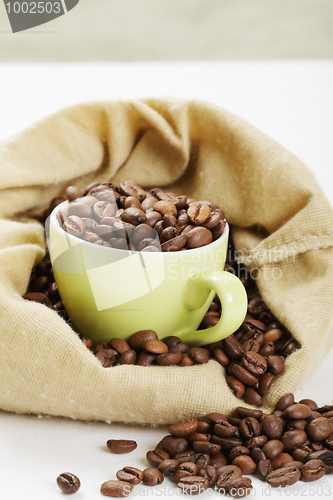 Image of Green cup filled with coffee beans in bag