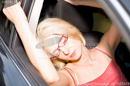 Image of young beautiful woman resting in the car under sun
