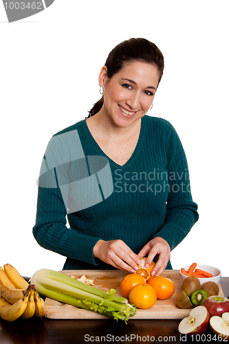 Image of Woman in kitchen peeling orange
