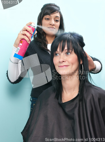 Image of Hair stylist sprays customer's hair