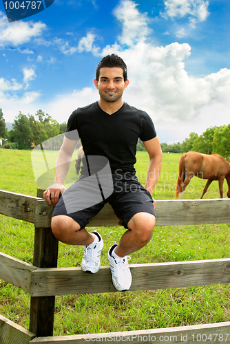 Image of Man sitting on fence countryside