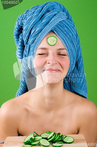 Image of smiling woman in blue towel and mask from cucumber