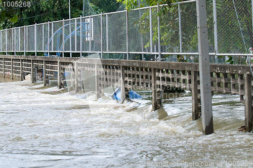 Image of Water flowing through a broken fence during a flood