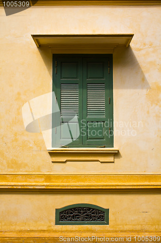 Image of green window shutters on yellow wall with great shadows 
