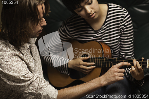 Image of Young Musician Teaches Female Student To Play the Guitar