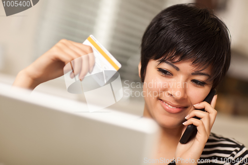 Image of Multiethnic Woman Holding Phone and Credit Card Using Laptop