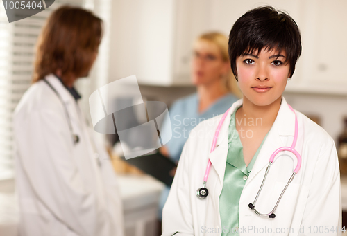 Image of Pretty Latino Doctor Smiles at Camera as Colleagues Talk
