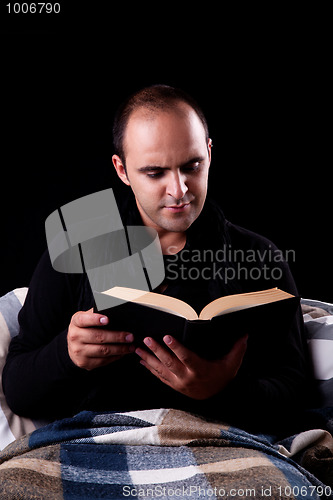 Image of man lying on the couch reading a book