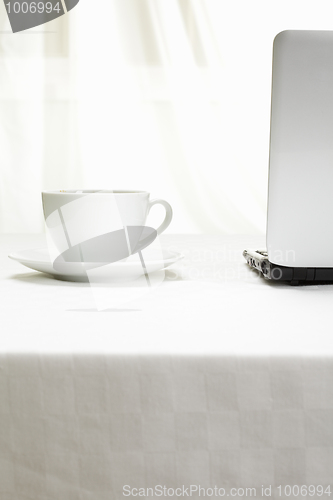 Image of Coffee and laptop on white tablecloth