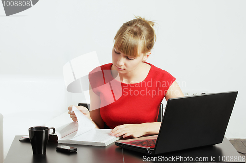 Image of Blonde woman reading magazine at desk