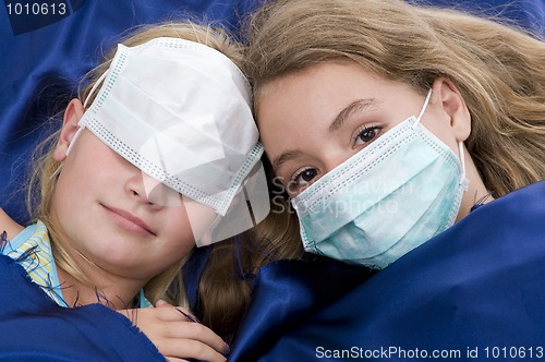 Image of sisters in bed with protective mask