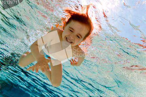 Image of The girl smiles, swimming under water in the pool