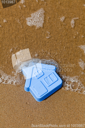 Image of Plastic toy house lies on the sand