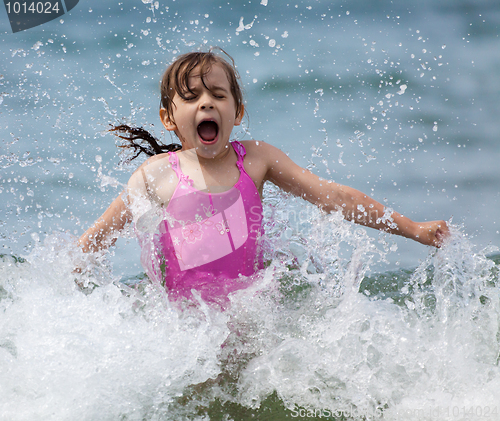 Image of Little girl laughing and crying in the spray of waves