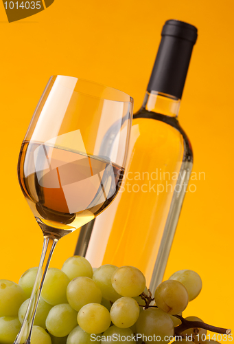 Image of Bottom view of a glass of white wine bottle and grapes 