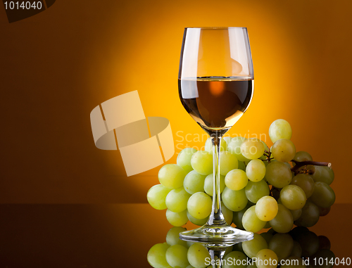 Image of A glass of white wine and a bunch of green grapes