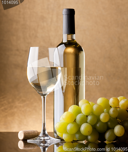 Image of A bottle of white wine, glass and grapes