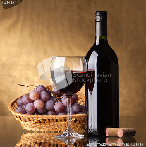 Image of A bottle of red wine, glass and grapes