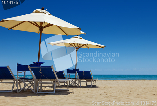 Image of Deck chairs under an umbrella in the sand