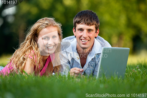 Image of A couple relaxing in the park with a laptop