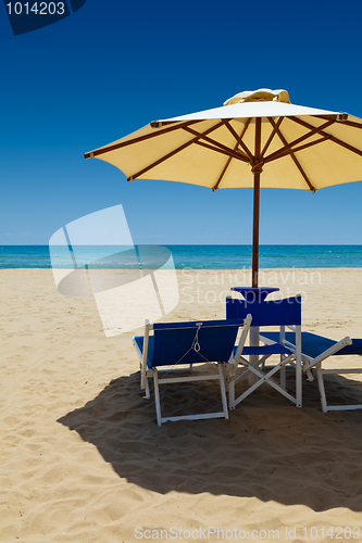 Image of Deck chairs under an umbrella in the sand