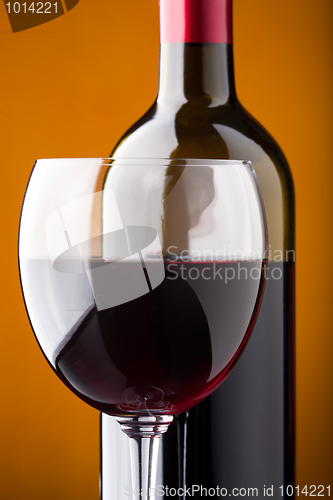 Image of A bottle of red wine and a wine glass closeup