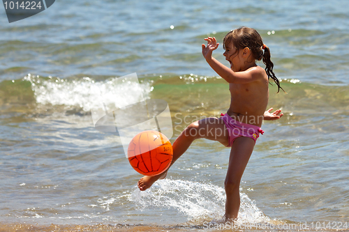 Image of The little girl on the beach hit the ball