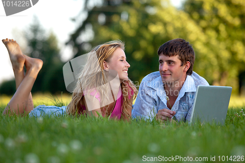 Image of A couple relaxing in the park with a laptop