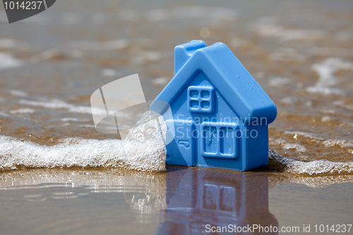 Image of Toy plastic house on the sand washes wave