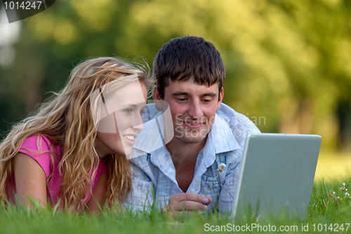 Image of A couple relaxing in the park with a laptop