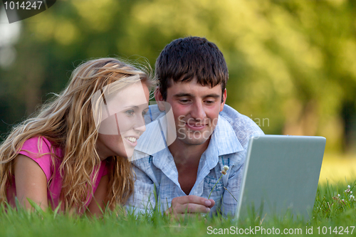 Image of A couple relaxing in the park with a laptop