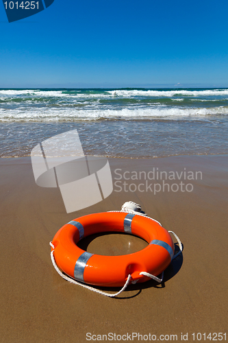 Image of Red lifebuoy lying on the sand on the beach