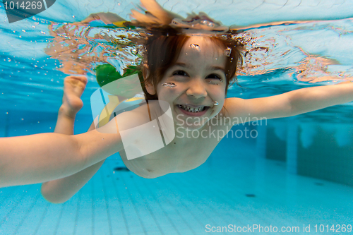 Image of The girl smiles, swimming under water in the pool