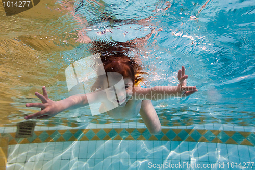 Image of The girl smiles, swimming under water in the pool