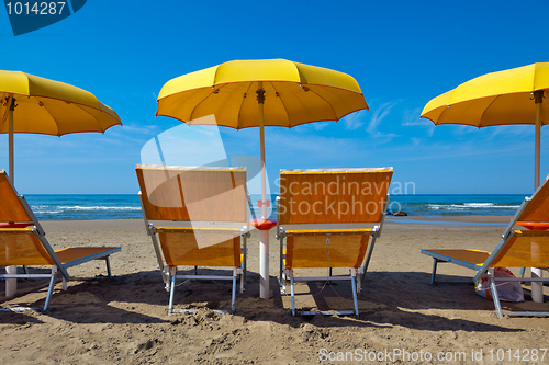 Image of Lounge chairs under a yellow umbrella