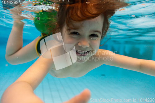 Image of The girl smiles, swimming under water in the pool