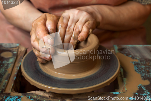 Image of Potter creates a pitcher on a pottery wheel